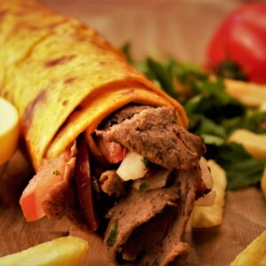 Close-up of a flavorful Turkish kebab wrap with fresh fries and vegetables.