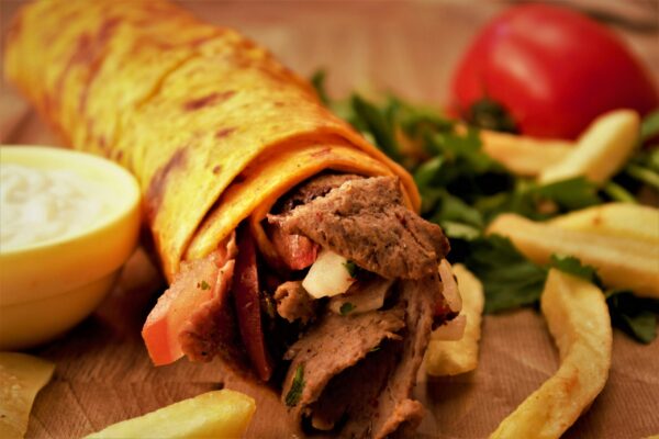 Close-up of a flavorful Turkish kebab wrap with fresh fries and vegetables.