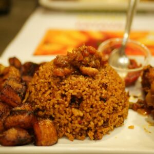 A tempting plate of Jollof rice accompanied by savory fried plantains. Perfect meal idea.