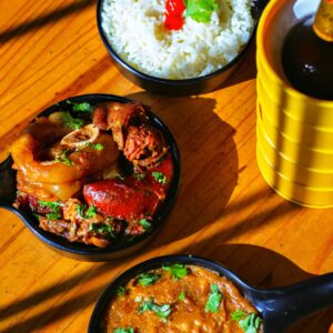 Delicious Indian dishes with rice and curry served in black bowls on a wooden table.