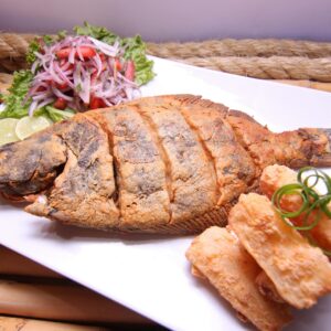 Delicious golden fried fish served with fresh salad and crispy sides, perfect for a Peruvian meal.