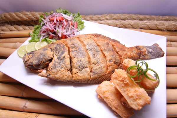 Delicious golden fried fish served with fresh salad and crispy sides, perfect for a Peruvian meal.