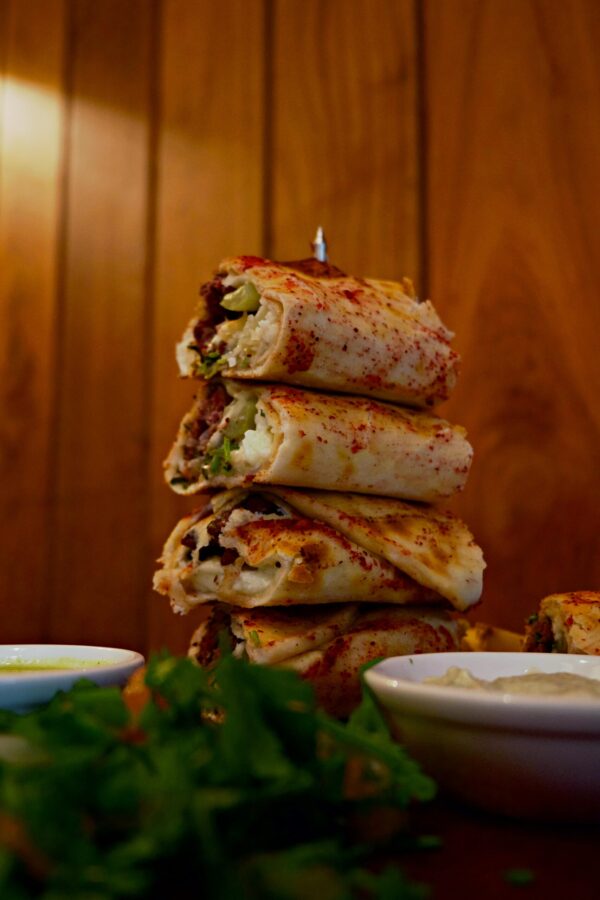 A vertical stack of flavorful shawarma served with fresh herbs and sauces, showcasing Middle Eastern cuisine.