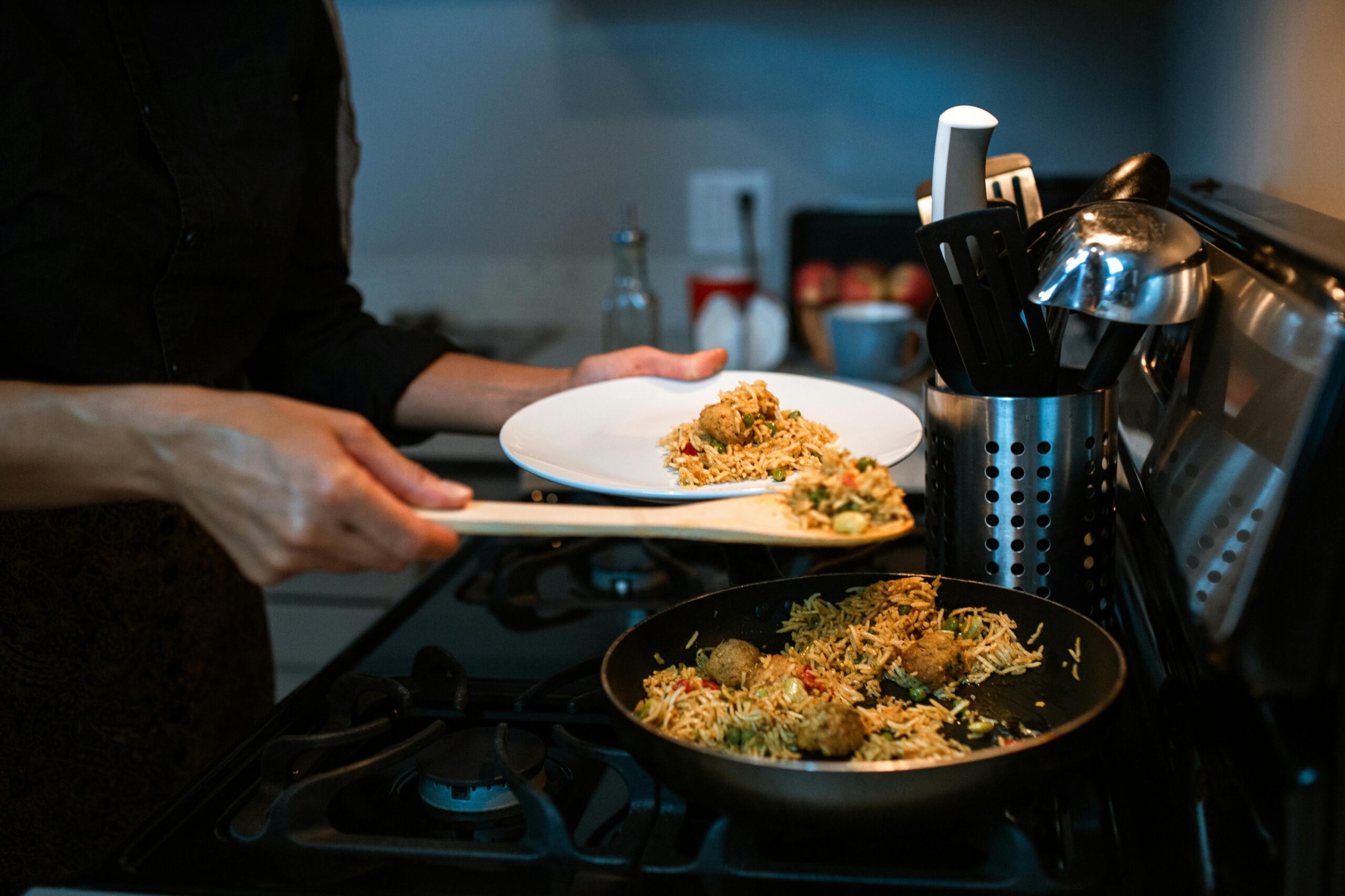 Close-up of a person serving delicious home-cooked fried rice from a pan in a kitchen setting.