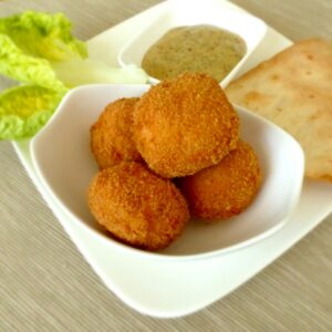 A delicious plate of crispy chicken bites served with sauce, crispy bread, and fresh lettuce.